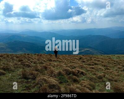 Vue lointaine du randonneur standing on mountain contre ciel nuageux Banque D'Images