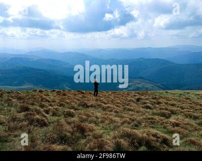 Vue lointaine du randonneur standing on mountain contre ciel nuageux Banque D'Images