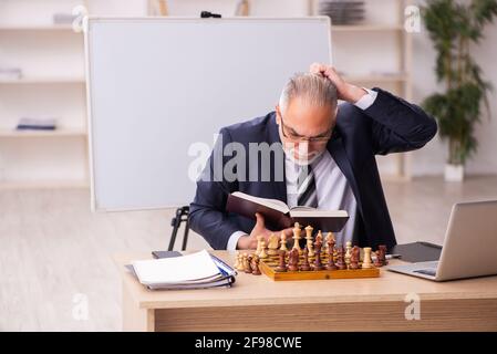 Un vieux employé d'homme d'affaires jouant aux échecs sur le lieu de travail Banque D'Images