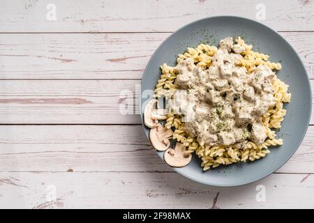 Tagliatelle pâtes italiennes avec champignons champignon blanc de la forêt sauce crémeuse et poulet ou viande de bœuf - plats faits maison dans l'assiette sur la vue du dessus de la table Banque D'Images