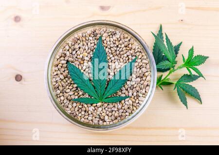 Graines de cannabis dans un bol en verre et feuilles de chanvre riches en protéines et graisses saines Banque D'Images