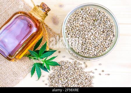 Graines de cannabis dans un bol en verre sur la table et le tissu de chanvre avec de l'huile riche en protéines et des graisses saines Banque D'Images