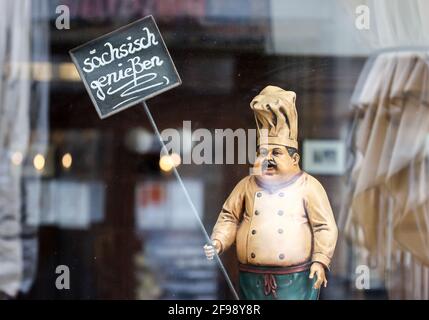 Leipzig, Allemagne. 15 avril 2021. La figure d'un cuisinier porte un panneau 'sächsisch genießen' (Profitez de la Saxe) dans la fenêtre d'un restaurant fermé en raison de corona. Credit: Jan Woitas/dpa-Zentralbild/ZB/dpa/Alay Live News Banque D'Images