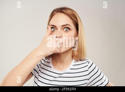 Blond gai sur un fond clair montre un doigt et Un t-shirt court à rayures est visible Banque D'Images