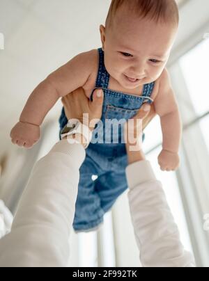 Portrait à la maison d'un bébé garçon avec mère sur le lit. Maman tenant et embrassant son enfant. Concept de fête des mères Banque D'Images