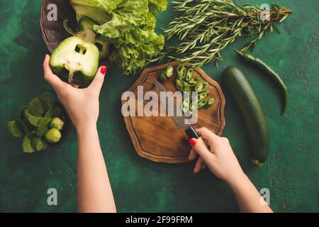 Femme coupant des poivrons verts sur fond de couleur Banque D'Images