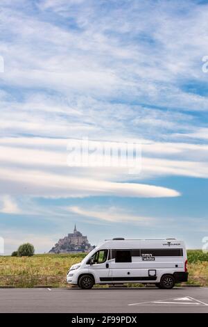 Motorhome / Van 'Vantourer Noir et blanc' en face de la magnifique île historique des marées et de la forteresse le Mont-Saint-Michel. Le monument est classé au patrimoine mondial de l'UNESCO en Normandie, France Banque D'Images