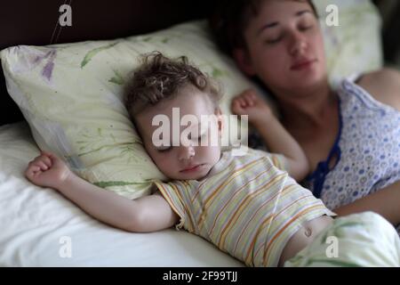 La mère avec un enfant dorment sur un lit dans le matin Banque D'Images