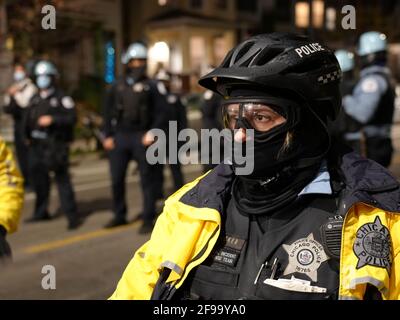 Chicago, États-Unis. 16 avril 2021. Un policier se tient devant les manifestants lors d'une manifestation à Chicago, aux États-Unis, le 16 avril 2021. Des centaines de manifestants se sont rassemblés vendredi soir dans un parc au nord-ouest de Chicago pour protester contre le meurtre par la police d'Adam Toledo, âgé de 13 ans, le 29 mars. Credit: Marcus DiPaola/Xinhua/Alamy Live News Banque D'Images