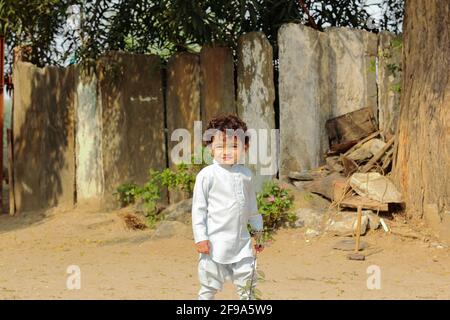 Un enfant indien souriant à la caméra debout devant la cour extérieure. Banque D'Images