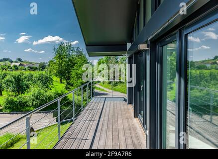 Façade vitrée avec terrasse en bois sur une maison unifamiliale dans le vert Banque D'Images