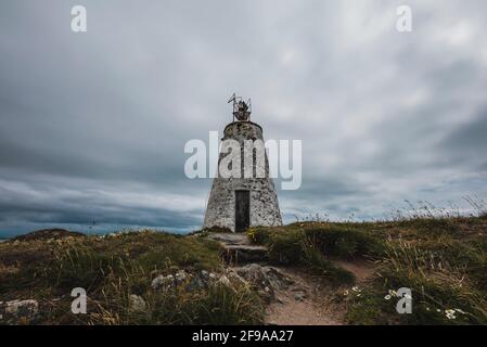 Ancienne tour en pierre sur la côte de l'îlot de Ynys Llanddwyn contre un ciel nuageux Banque D'Images