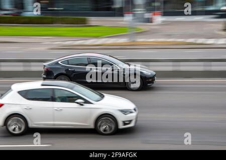 Ukraine, Kiev - 29 septembre 2020: Black Tesla modèle 3 VS White Seat Leon voiture se déplaçant dans la rue Banque D'Images