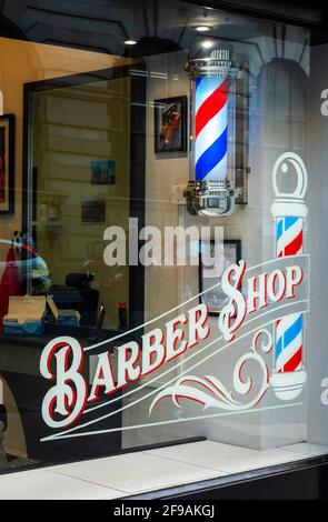 Fenêtre du salon de coiffure et barre de coiffeur rouge, blanche et bleue. Banque D'Images