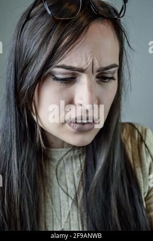 Portrait d'une belle jeune femme aux longs cheveux bruns avec un regard froid parce qu'elle est gêné par quelque chose Banque D'Images