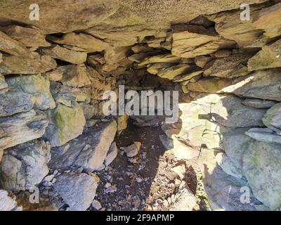 Petite grotte avec plusieurs pierres empilées les unes sur les autres illuminées par la lumière du soleil : Banque D'Images