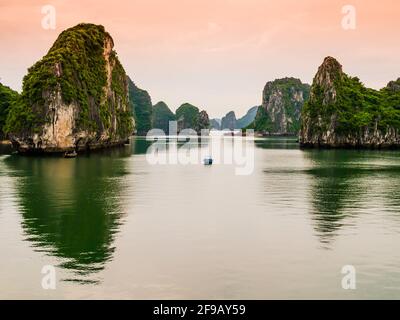 Vue imprenable sur les formations karstiques de la baie d'Halong se reflétant dans les eaux émeraude du golfe de Tonkin, au Vietnam Banque D'Images