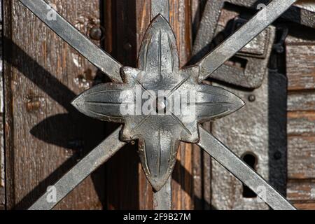 La vieille porte avec une poignée en fer forgé derrière une treillis de fer avec décoration, gros plan. Banque D'Images