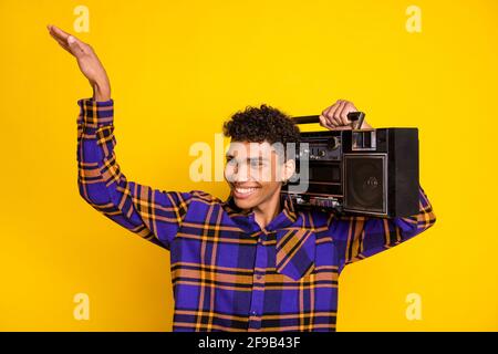 Photo portrait d'un beau gars souriant en gardant un magnétophone rétro l'espace est vide et la danse est isolée sur fond jaune vif Banque D'Images