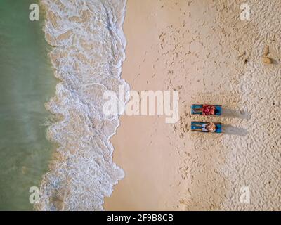 Aruba Caribbean couple homme et femme de milieu d'âge en vacances sur la plage avec des palmiers sur la plage Banque D'Images