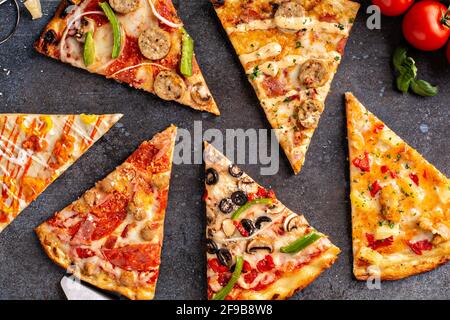 Variété de tranches de pizza vue de dessus sur fond sombre Banque D'Images