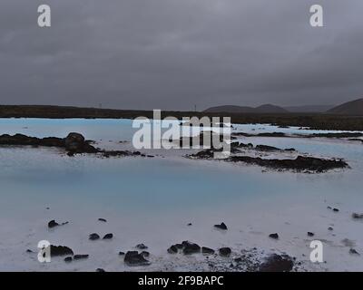 Piscines d'eau thermale de couleur bleue et de dépôts blancs entourés de champs de lave et de roches volcaniques près de la station thermale géothermique Blue Lagoon, Islande. Banque D'Images