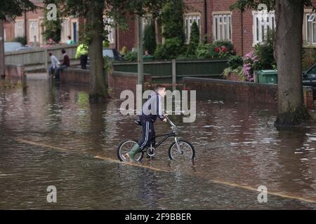 Un garçon à vélo dans les eaux inondées, Abingdon Road, à l'ouest d'Oxford, après des pluies torrentielles non saisonnières qui ont conduit à la Tamise et à ses affluents à briser leurs berges. 250 maisons dans la région d'Abingdon et de Botley Road à l'ouest d'Oxford où il a été évacué. Abingdon Road, Oxford, Royaume-Uni. 23 juillet 2007 Banque D'Images