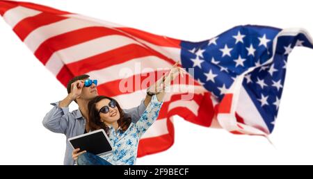 Insouciant et amoureux. Jeune couple funky couvert de drapeau américain et souriant tout en se tenant sur fond blanc Banque D'Images