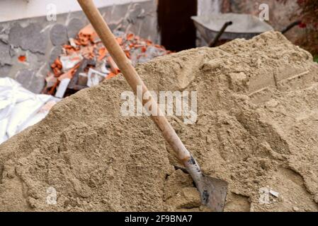 Gros plan d'une pelle coincée dans un tas de sable sur un chantier de construction Banque D'Images