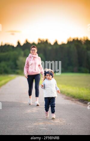 Mère et enfant marchant sur la route de campagne entre les champs agricoles vers le vilage de la forêt. Banque D'Images