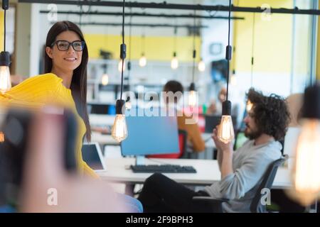 Portrait d'une jeune femme d'affaires décontractée et heureuse debout avec un ordinateur portable sur son lieu de travail dans un espace de travail moderne. Banque D'Images