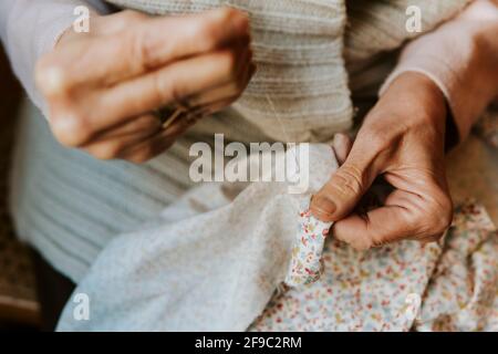 Gros plan sur les mains de la femme en train de coudre avec l'aiguille et filetage Banque D'Images