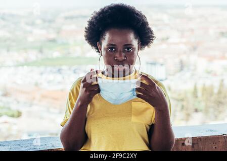 Portrait d'une fille noire afro-américaine mettant sur son masque facial. Banque D'Images