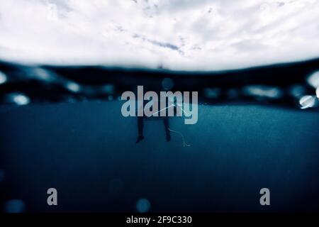 garçon surfeur calme assis sur le dessus de la planche, sous l'eau, vague Banque D'Images