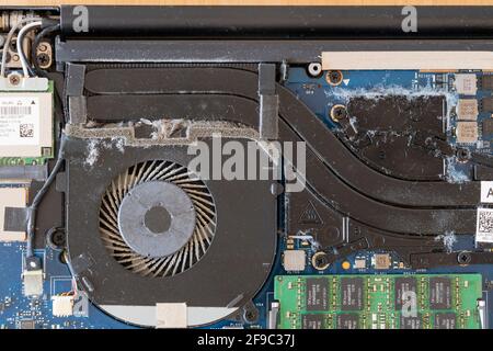 Un gros plan à l'intérieur d'un ordinateur portable rempli de poussière et de débris qui doivent être nettoyés à partir du ventilateur et des composants électriques Banque D'Images