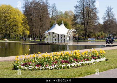 Le kiosque à musique couvert et le lac de navigation dans le parc d'Eastrop avec des fleurs printanières au premier plan. Avril 2021. Basingstoke, Royaume-Uni Banque D'Images