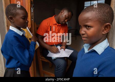 Dodoma, Tanzanie. 08-18-2019. Un groupe d'enfants noirs est réuni avec leur professeur d'école qui est assis à l'intérieur de la salle de classe regardant ses élèves Banque D'Images