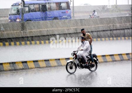 Les navetteurs qui passent par la route pendant une grosse descente à Lahore le samedi 17 avril 2021. Banque D'Images