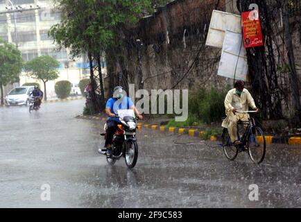 Les navetteurs qui passent par la route pendant une grosse descente à Lahore le samedi 17 avril 2021. Banque D'Images