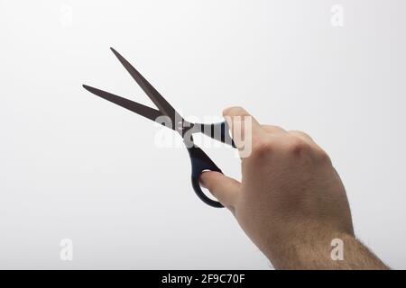 La main tient une paire de ciseaux isolée sur un fond blanc. Ciseaux de papeterie à la main isolés sur fond blanc. Banque D'Images