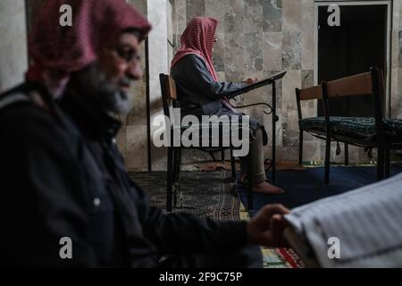 Maarrat Misrin, Syrie. 17 avril 2021. Des hommes syriens lisent le Coran à la mosquée de la ville de Maarrat Misrin, pendant le mois musulman de jeûne du Ramadan. Credit: Aras Alkharboutli/dpa/Alamy Live News Banque D'Images
