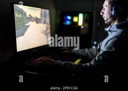 Joueur professionnel ou Streamer jouant jeu vidéo en ligne de jeu de tir à la première personne sur un PC de jeu personnalisé. Il porte un casque Banque D'Images