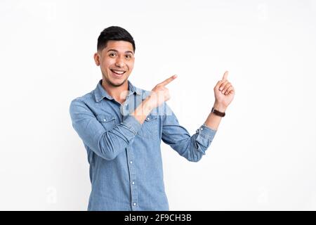 Homme caucasien pointant ses deux doigts sur le côté et sourire à l'appareil photo avec un arrière-plan blanc Banque D'Images