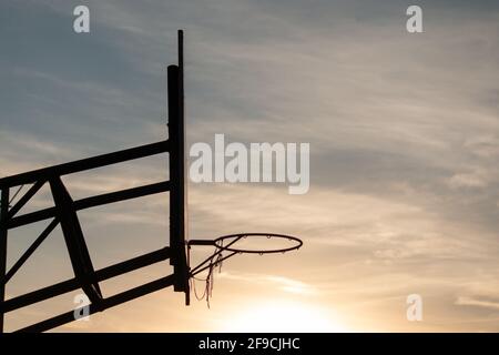 Image sous-exposée d'un fond de panier de basket-ball avec un panier contre un ciel sombre de coucher de soleil Banque D'Images
