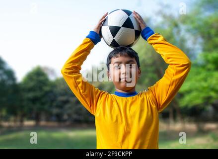 Portrait of boy holding soccer ball on head Banque D'Images