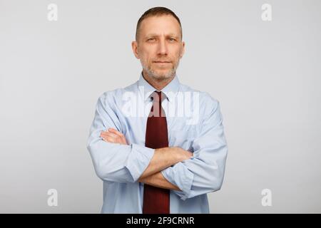 Un homme d'affaires d'un âge moyen et sérieux pose sur fond blanc. Banque D'Images