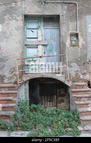 Porte fermée abandonnée, avec escalier, balcon, mains courantes, boîte à fusibles et signe de paix sur une porte en bois Banque D'Images