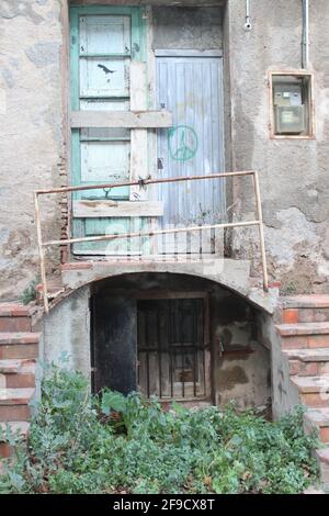 Porte fermée abandonnée, avec escalier, balcon, mains courantes, boîte à fusibles et signe de paix sur une porte en bois Banque D'Images