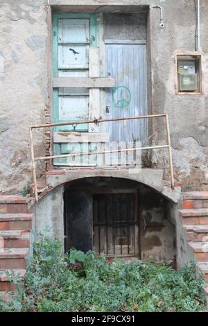 Porte fermée abandonnée, avec escalier, balcon, mains courantes, boîte à fusibles et signe de paix sur une porte en bois Banque D'Images