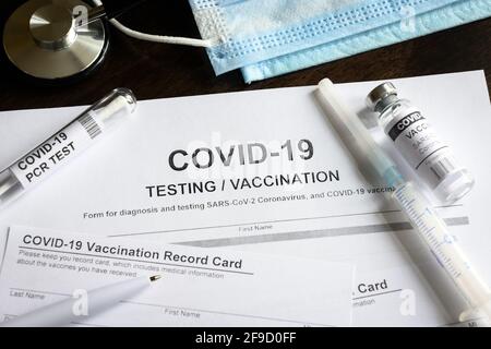 Formulaire médical de test et de vaccination COVID-19 sur bureau, kit d'injection du vaccin contre le coronavirus et certificat de vaccination sur bureau. Concept de virus corona Banque D'Images